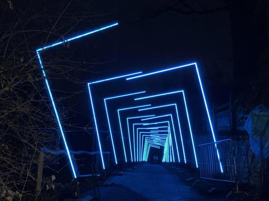 A path surrounded by half door frames left and right, which are illumated in blue right now. Create some sort of tunnel effect.