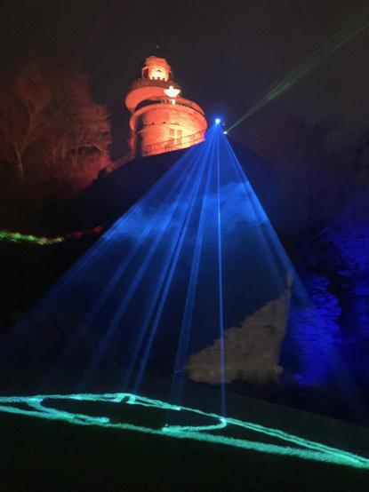 The illuminated Emichsburg with blue laser beams shining from above to the ground.